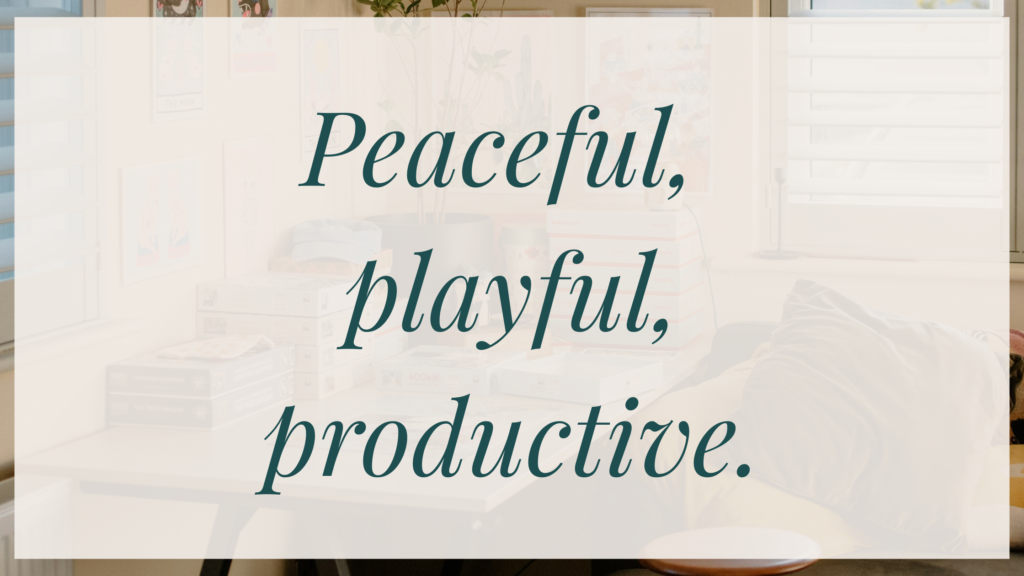 Home Softly lit home workspace with a desk, books, and wall art in the background, overlaid with the text “Peaceful, playful, productive.”
